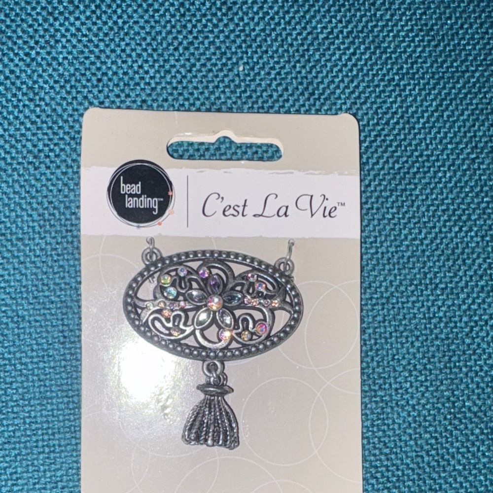 Antiqued silver rhinestone floral design oval pendant with tassel